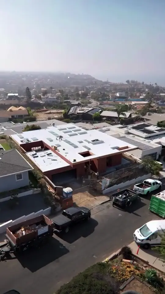 Coastal flat roof — White membrane on a hillside modern with the ocean beyond.